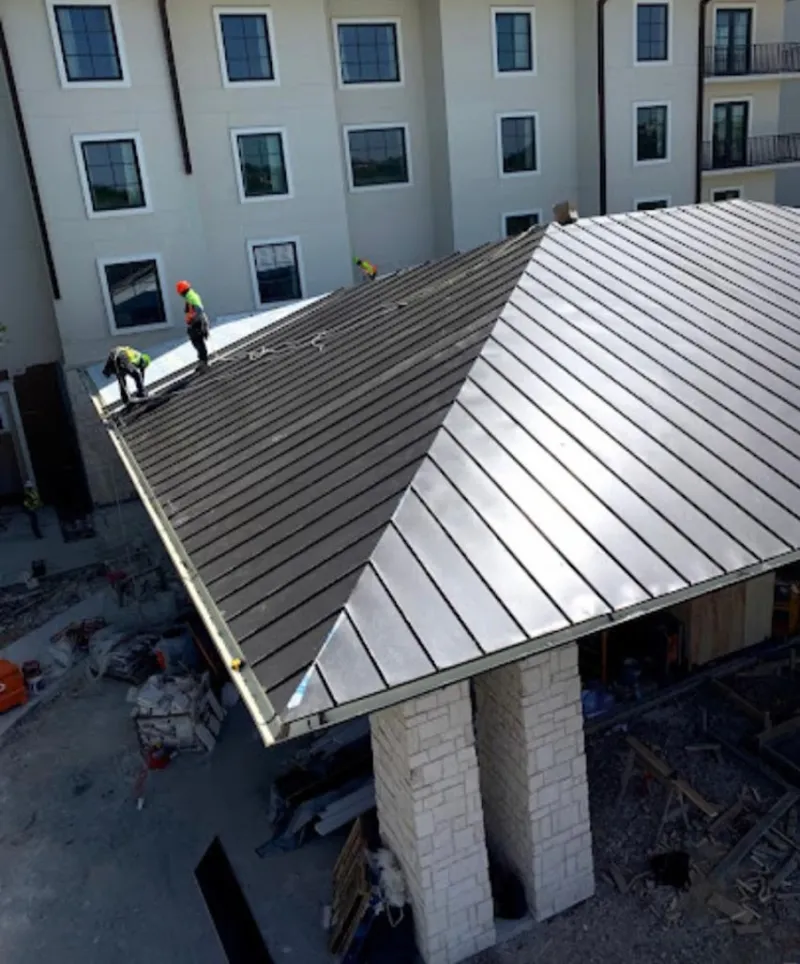 Crew installing standing seam metal roof panels on a commercial project in Cheektowaga